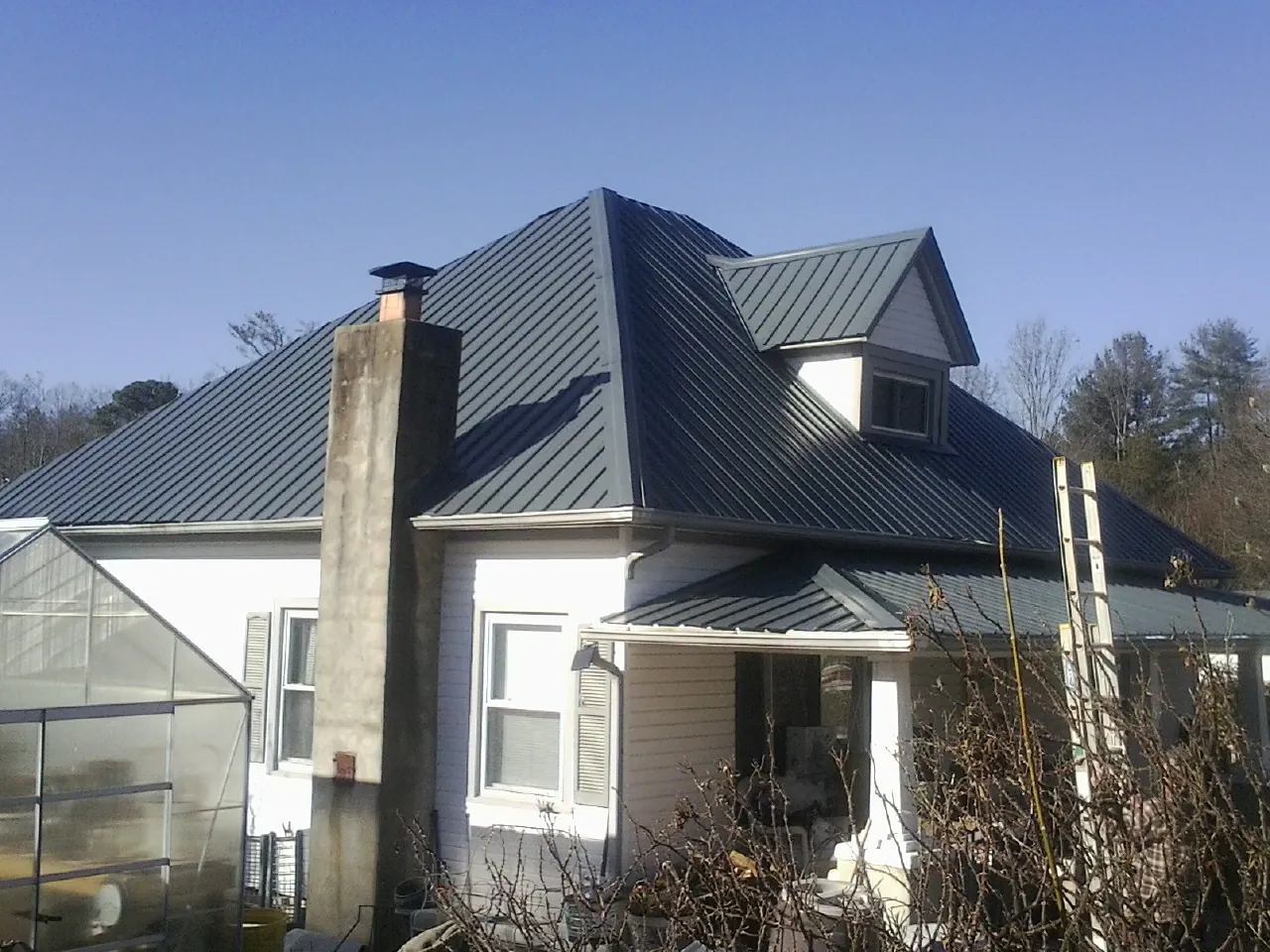 Dark blue standing seam metal roof on a white farmhouse with dormer — Slate & Tile Roof Repair by Roofing Brothers in Santa Cruz
