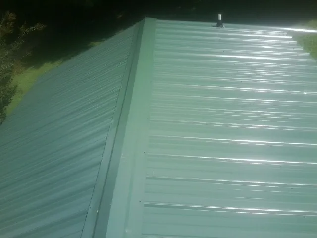 New green metal panels meeting at the ridge of a roof — Flat Roof Repair work by our crew in Santa Cruz