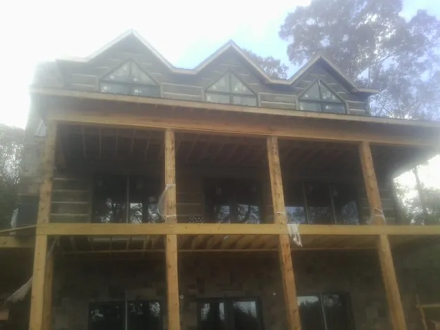 Dormers and porch framing on a large log home under construction — Roof Coating work by our crew in Santa Cruz