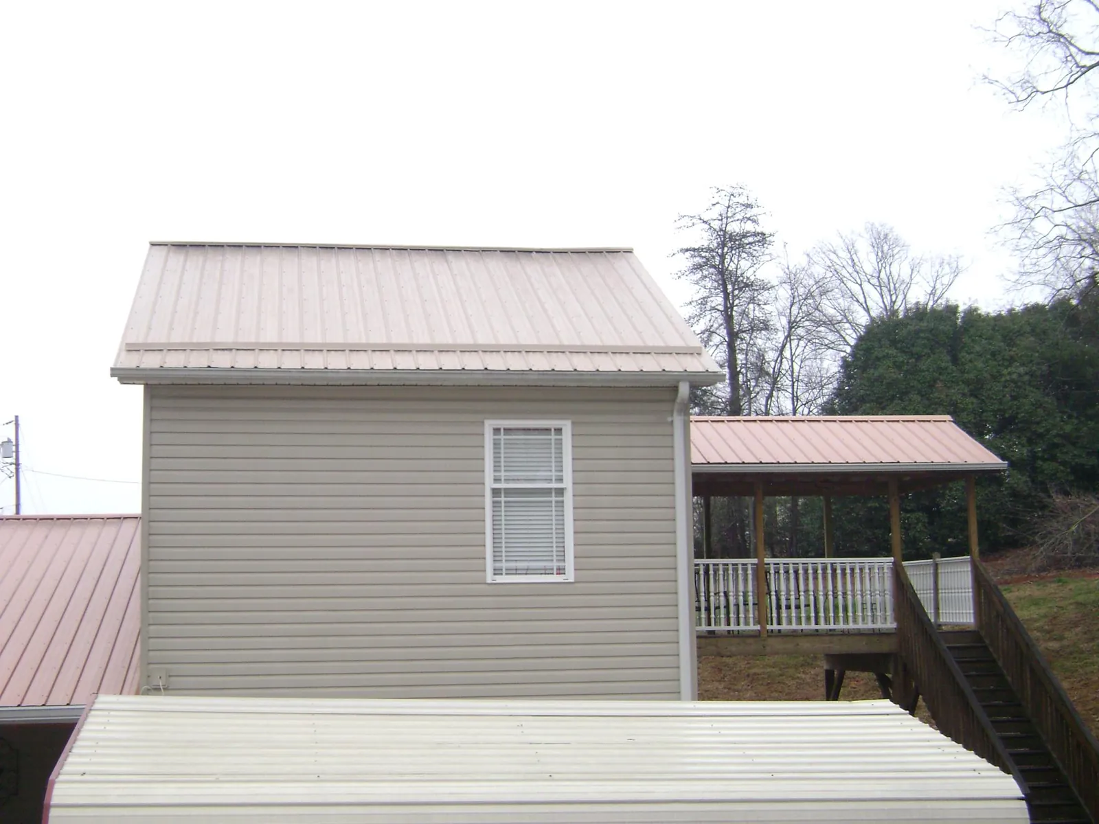 Tan metal roofs on a two story addition and attached porch, from a Roof Replacement job in Santa Cruz