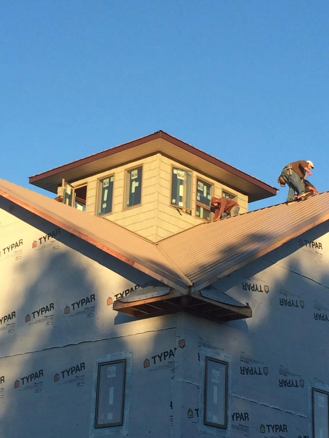 Roofers working around a rooftop cupola on a new metal roof at sunset — Roof Waterproofing in Santa Cruz by Roofing Brothers